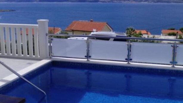 A swimming pool with a view of the sea and distant hills.