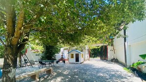 A courtyard with a small white building, a tree, and outdoor furniture. - Quinta "Los Tercos (Santiago)