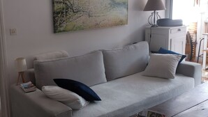 A living room with a grey sofa, a lamp, and a painting on the wall. - Quiet village center and seaside T2 apartment with swimming pool and private parking. (Fréjus)