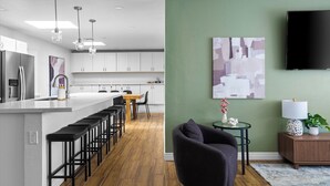 A modern kitchen with a long island, bar stools, and pendant lighting.