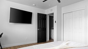 A bedroom with a bed, a TV mounted on the wall, and a door leading to a bathroom.