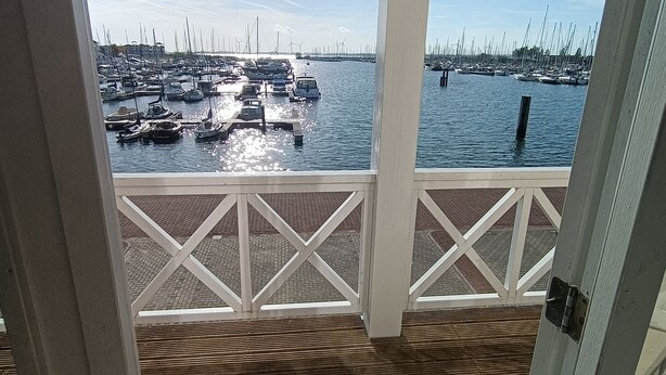 A wooden deck with a view of a marina filled with boats and a bridge in the distance. - 1st line water front 5 Minutes to the beach and 10 mins to old town center. (Hellevoetsluis)