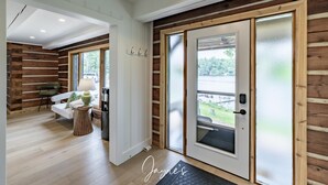 Un interior modern amb una paret de fusta, un sofà, una làmpada i una porta que dona a l'exterior.