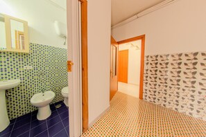 A narrow hallway with a bathroom on the left featuring a sink and toilet, and a patterned wall on the right. - The Stars - Frigento (Frigento)