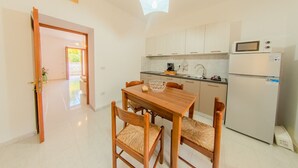 A compact kitchen with a dining table and chairs, a refrigerator, and a microwave. - The Stars - Frigento (Frigento)