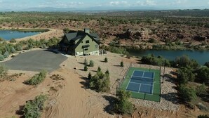 Uma casa com quadra de tênis e lago.