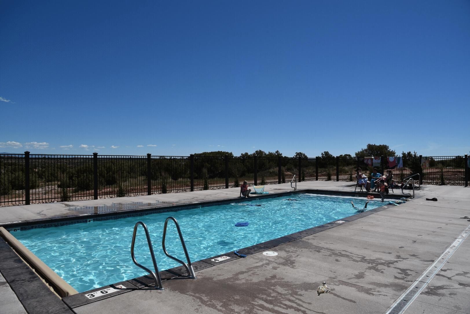 Une piscine rectangulaire entourée d’une clôture en métal noir.