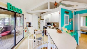A spacious kitchen with white cabinets, a large island, and a dining area with a red sofa.