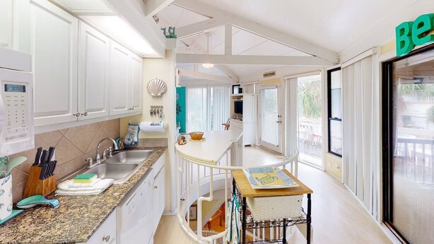 A modern kitchen with white cabinets, granite countertops, and a central island.