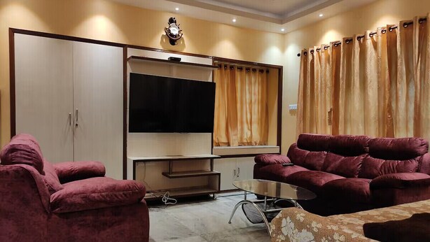 A living room with two red sofas, a TV, and a cabinet. - Luxury stay on budget (Kolkata)