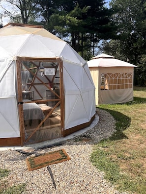 Une structure en forme de dôme géodésique, avec un intérieur en bois, une porte et un panneau indiquant le numéro 6.