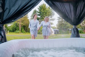 Two people walking towards a hot tub with a gazebo in the background.