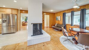 Een moderne keuken met een ingebouwde open haard, houten vloeren en een eethoek met een ronde tafel en stoelen.