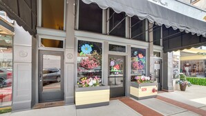 Un escaparate con un cartel de bolsa de danza, una maceta con flores y una puerta que indica "Avelan Suites".