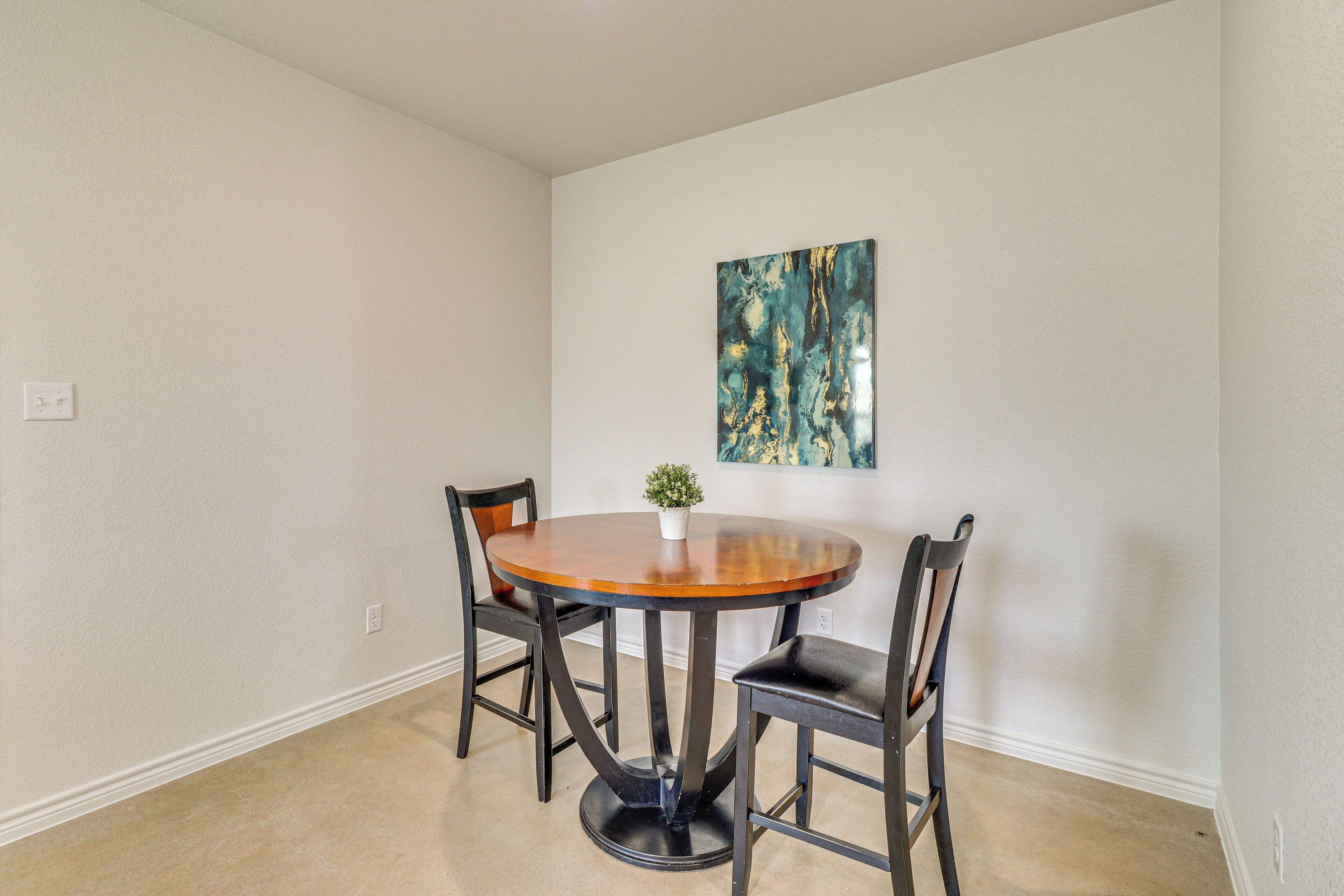A dining area with a round table, four chairs, and a small potted plant.