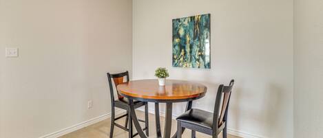 A dining area with a round table, four chairs, and a small potted plant.