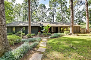 A modern house with a stone pathway leading to the entrance, surrounded by a well-maintained garden and tall trees. - Secluded Lake Hamilton Access: Hot Springs Home (Hot Springs)