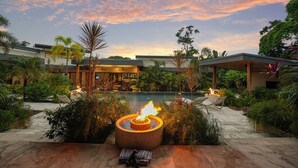 A poolside area with a fire feature, outdoor seating, and lush greenery.