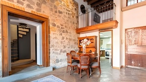 A dining area with a stone wall, wooden furniture, and a view into the kitchen.