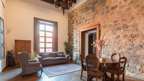 A cozy living room with a stone wall, a sofa, a coffee table, and a dining area with chairs.