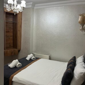 A hotel room with a bed, a wooden wardrobe, a radiator, and a chandelier. - Nova Roma Hotel Istanbul (Istanbul)