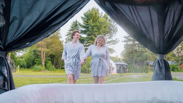 Zwei Personen gehen in Richtung eines Außen-Whirlpools, im Hintergrund ein Pavillon.