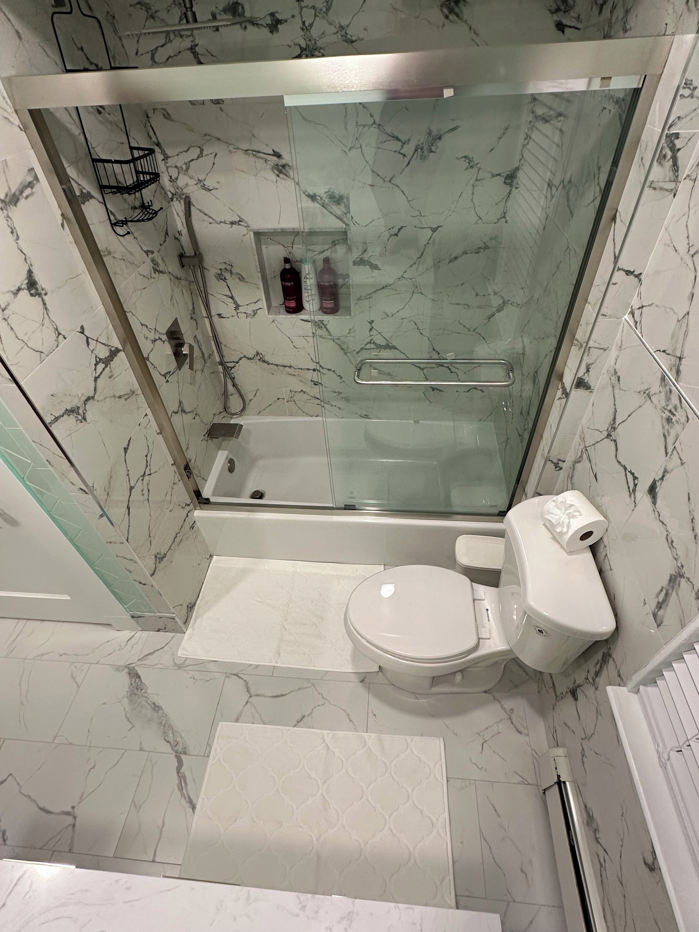 A modern bathroom with a glass-enclosed shower, a toilet, and a sink.