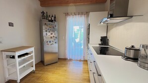 Una cocina compacta con refrigerador, cafetera y una pequeña mesa con botellas de vino.