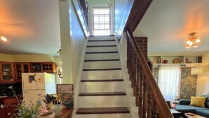 A staircase with wooden steps and a wooden handrail, leading to a landing with a view of a window.