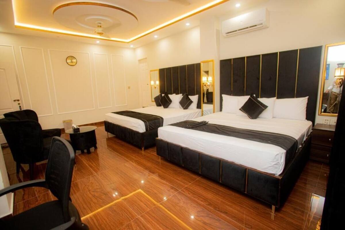 A hotel room with two beds, a desk, a chair, and a large mirror.
