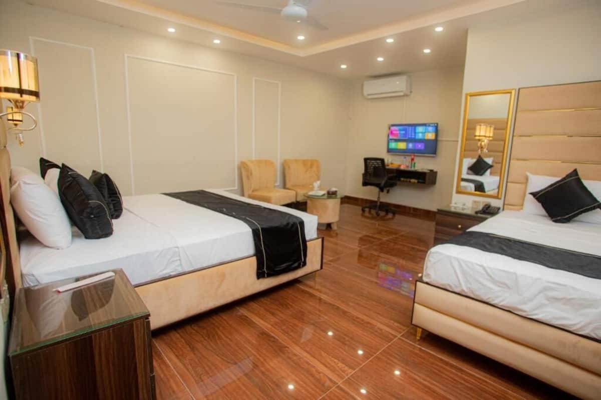 A hotel room with two beds, a desk, a chair, a TV, and a mirror.