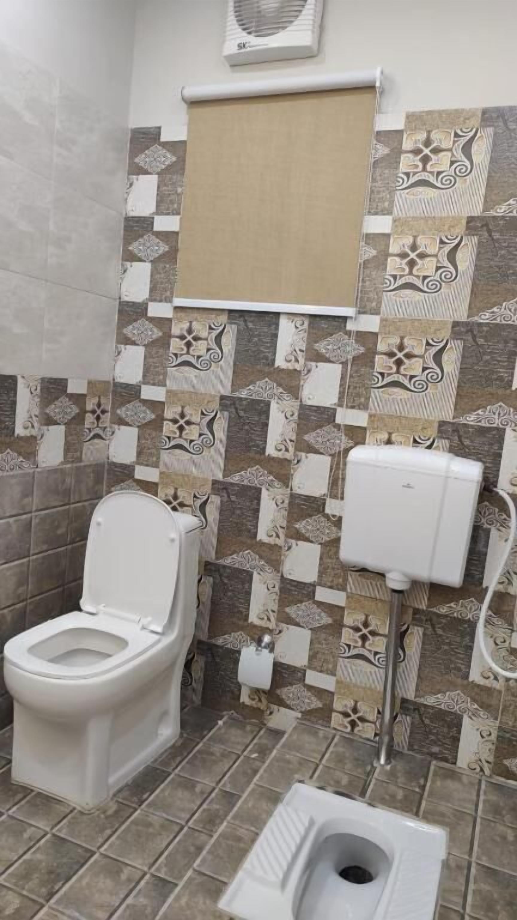 Et badeværelse med toilet, bidet og en vægmonteret luftfrisker.