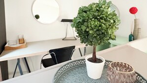 A small potted plant on a table, a round mirror on the wall, and a decorative bowl.
