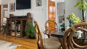 Un comedor con una mesa de madera, sillas y un televisor montado en la pared.