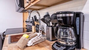 A kitchen with a coffee maker, utensils, and a knife block.