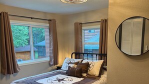 Une chambre avec un grand lit, un miroir rond et une fenêtre avec des rideaux.