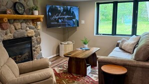 Un salon chaleureux avec une cheminée en pierre, un téléviseur à écran plat, un canapé confortable et une table basse.