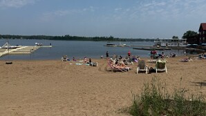 Une plage avec des transats et une jetée où sont amarrés des bateaux.