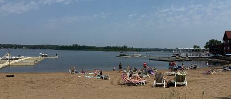 A beach with sun loungers and a dock with boats.