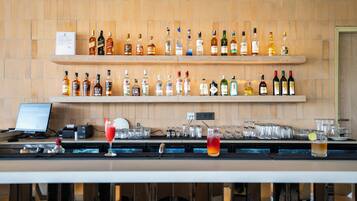 A bar area with shelves of liquor bottles, glasses, and a computer monitor.