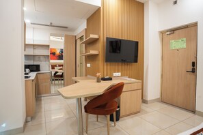 A modern kitchen with a wooden countertop, a TV mounted on the wall, and a door with a sign.