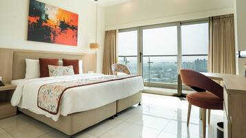 Une chambre d’hôtel avec un grand lit, un bureau, une chaise, une vue sur la ville et un tableau au mur.