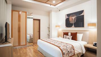 Une chambre d’hôtel moderne dotée d’un grand lit, d’une armoire en bois, d’un ventilateur de plafond et d’œuvres d’art abstraites.
