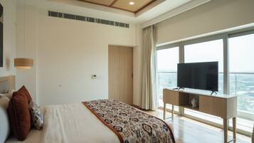 A bedroom with a bed, a television on a stand, a window with a view, and a ceiling with a wooden design.
