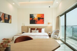 A modern hotel room with a large bed, a dining table, a chair, and a balcony with a city view. - AR Suites KLJ Square (Gurugram)