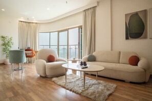 Un salon moderne avec un canapé, un fauteuil, une table basse et une grande fenêtre agrémentée de rideaux.
