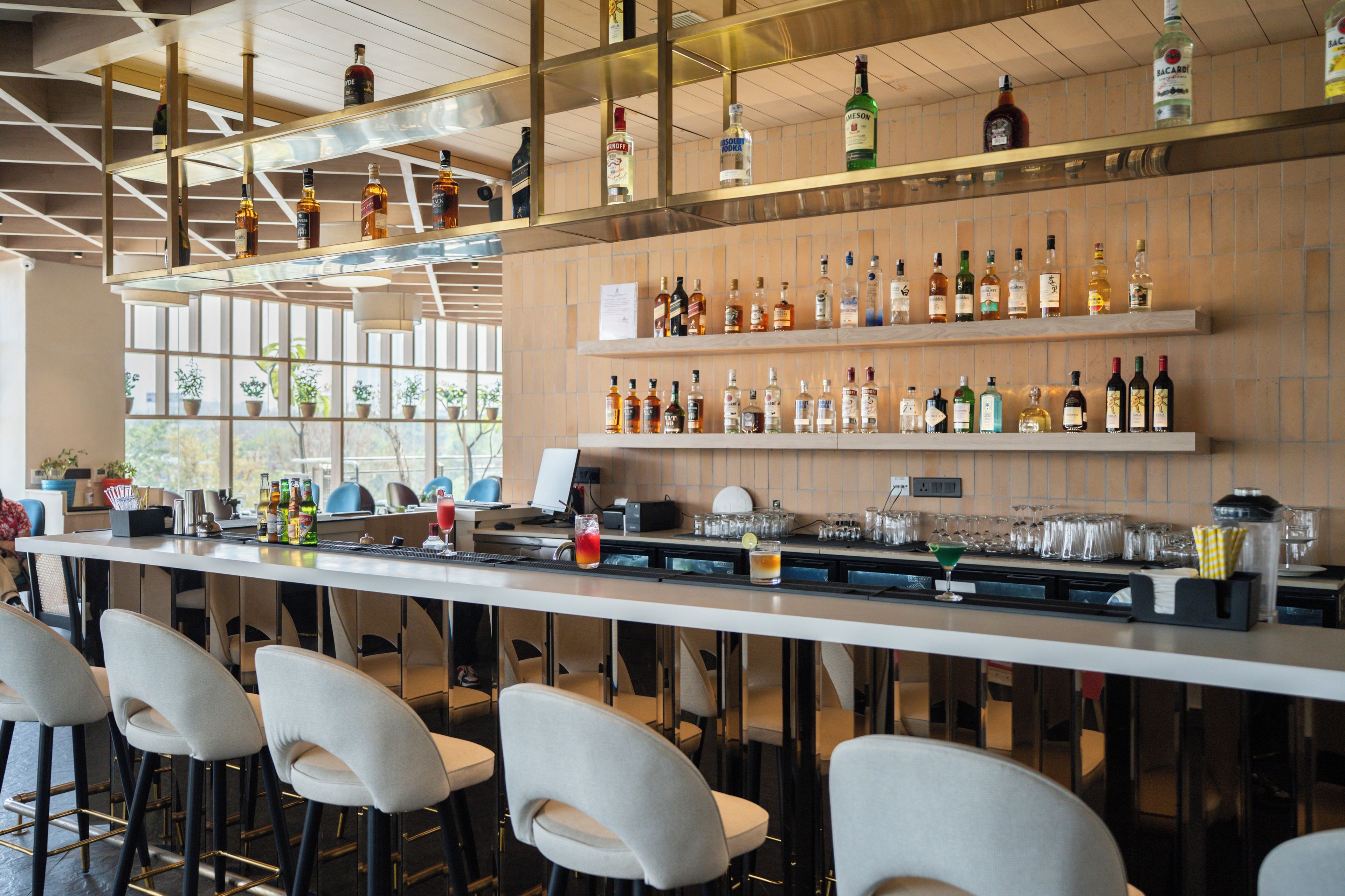 A bar area with multiple liquor bottles, glasses, and stools.
