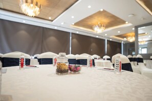 A conference room with round tables, chairs, and a chandelier. - AR Suites KLJ Square (Gurugram)