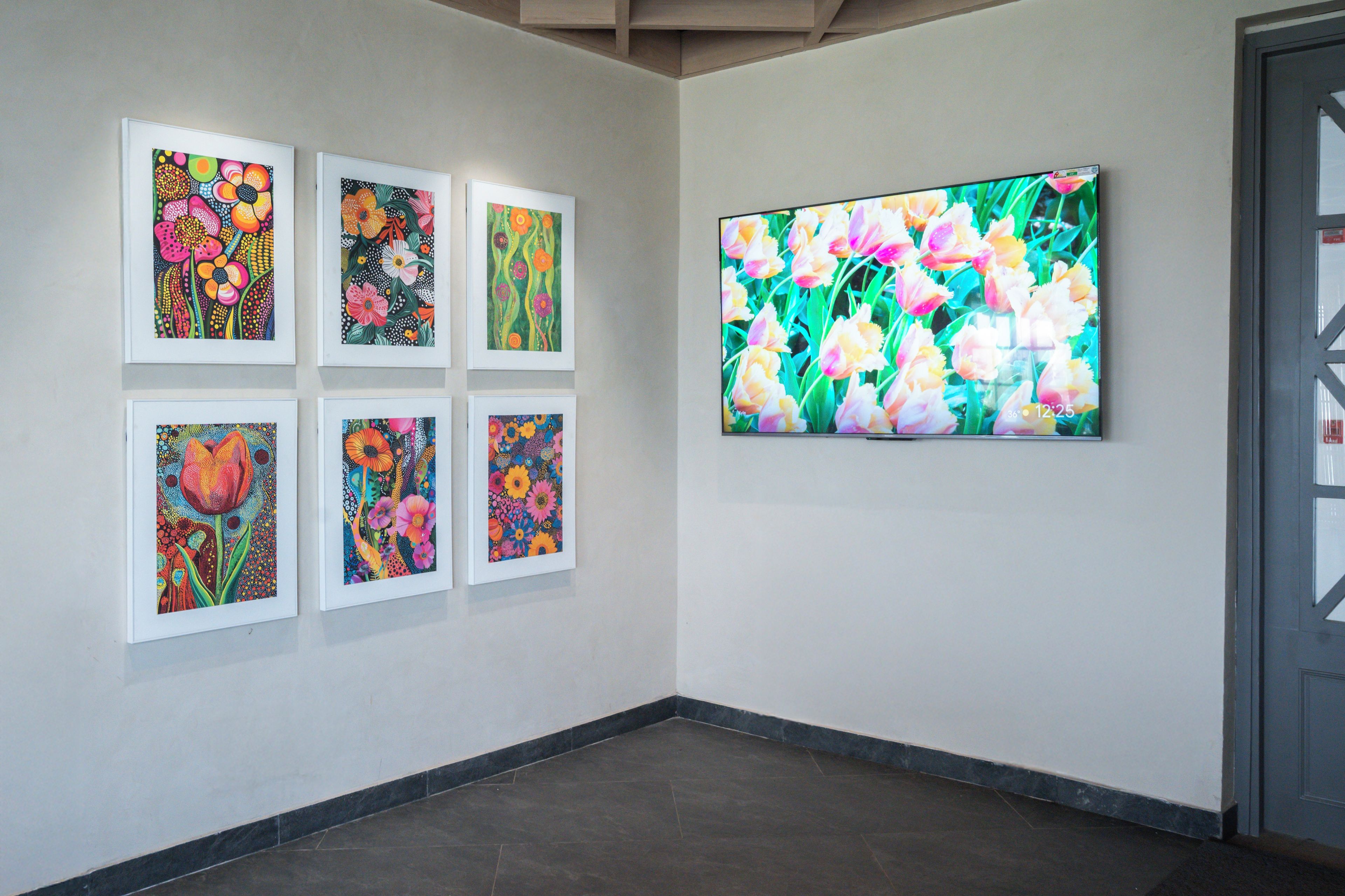 Una composición de galería con seis cuadros enmarcados de flores y una pantalla digital grande.