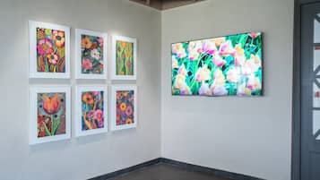 Una composición de galería con seis cuadros enmarcados de flores y una pantalla digital grande.
